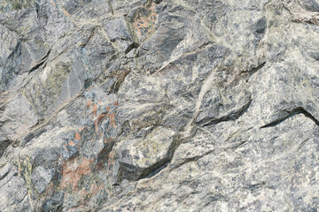 Texture of raw block of natural stone of greenish tint with brown inserts