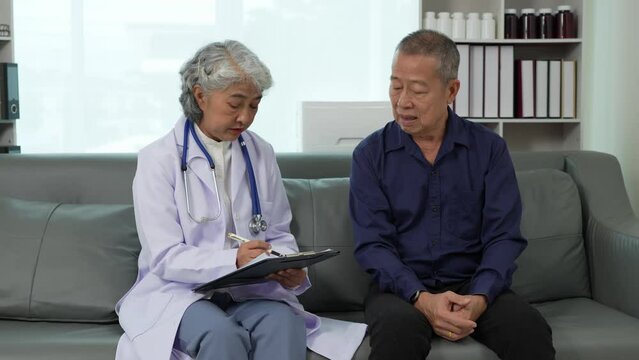 An elderly Asian male patient answers questions from an elderly female doctor. health advice and discuss comprehensive health care in a healthcare environment. Health insurance concept.