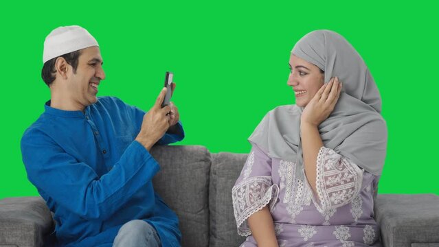 Happy Muslim husband clicking pictures of wife Green screen
