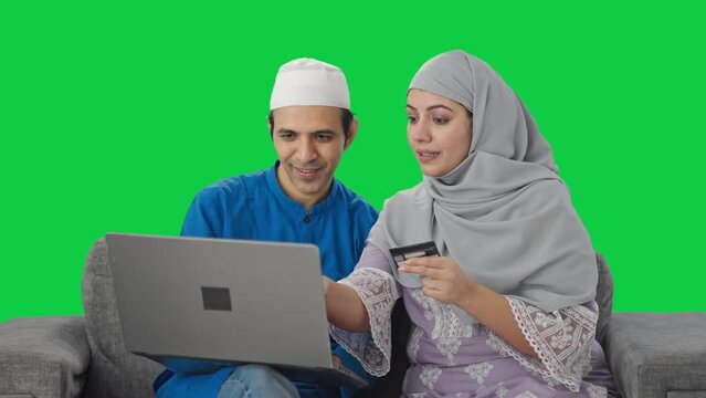 Muslim couple doing online shopping on laptop using credit card Green screen