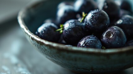  a close up of a bowl of blueberries with water droplets on the top of the bowl and on the bottom of the bowl.