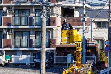 住宅街で電柱の上の電線の修理をする作業員