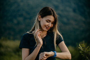 Caucasian woman jogging amidst nature, keeping track with her smartwatch