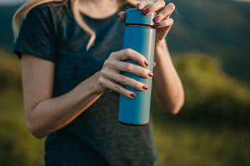 Active woman sips water, staying hydrated after jogging outdoor