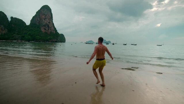 footage of a man model running on Railay beach in Krabi Thailand footage of incredible Thai landscapes incredible nature with insane rocks, jungle, ocean, sea. Filmed in 4k with smooth movement