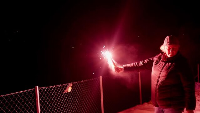 60 Year female holding marine distress flare next to fence on island, handheld