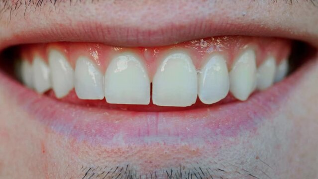 A close up of a man smiling with a small gap between in teeth