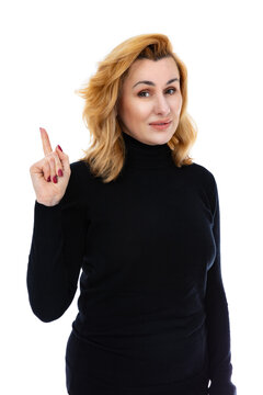 Portrait of forty year old woman pointing finger up to copy space, isolated on white background. Woman in black turtleneck act like a satisfied product, use for advertising posing in studio.