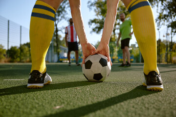 Soccer ball and sportsman legs over grass football field