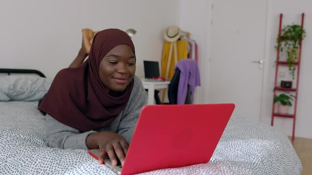 Happy young female student working on laptop at home. Millennial black girl using computer learning online. Education lifestyle concept. High quality 4k footage