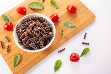 Organic Buckwheat Fusilli pasta, tomatoes cherry,basil leaf,on white background.Gluten free noodles.Healthy food concept