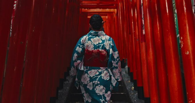 Shinto temple, woman and walk on stairs for religion ceremony in japan with Fushimi Inari Taisha Shrine, Torii Gates. Person, back or kimono for spiritual growth, kyoto or steps for spiritual peace