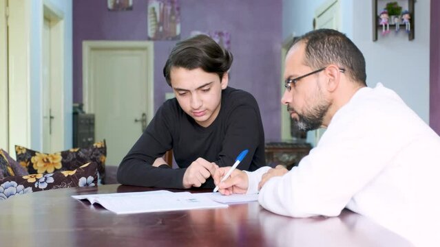 Arabic man teaching boy in his home