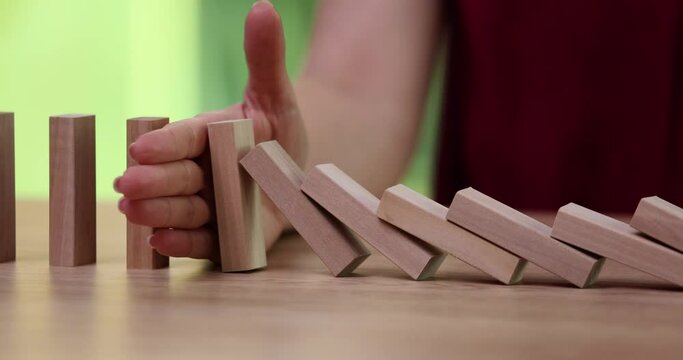 Problem solving closeup of business woman hand stopping blocks from falling on table