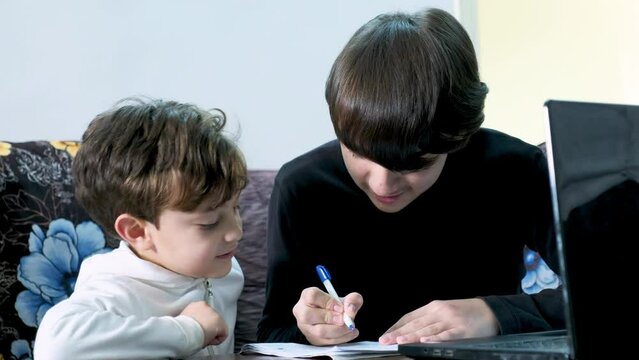 Arabic young brother teaching his smaller brother ,cheating while exams ,supporting for exams and make sure he grasp the concepts