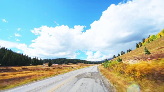 Kebler Pass, Colorado car driving vehicle shot on scenic drive dirt winding road in autumn fall, aspen pine tree forest by RV campground camping site