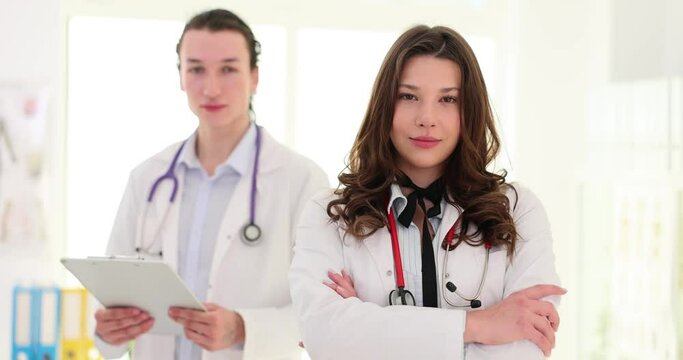 Handsome happy male doctor standing next to female colleague with crossed arms