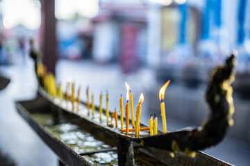 Row of burning of a lighted yellow wax candle placed on a candlestick  pay Candles to pay homage to...