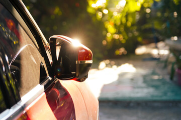 The sun shines down on the side mirror of the car. Sunlight reflected on the side mirror of a parked car.