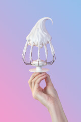 Woman's hand hold Whisk with cream, whisk with meringue cream isolated on gradient pink and blue vertical poster composition