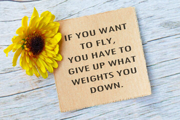 Naklejka premium Motivational quote on torn brown paper on wooden surface with sunflowers.