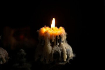 A burning candle in close-up, an antique candlestick covered with wax and cobwebs on a black...