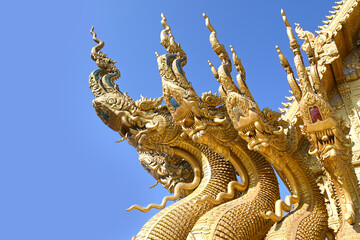 Fototapeta na wymiar Traditional thai dragon statue against blue sky at a temple in Thailand