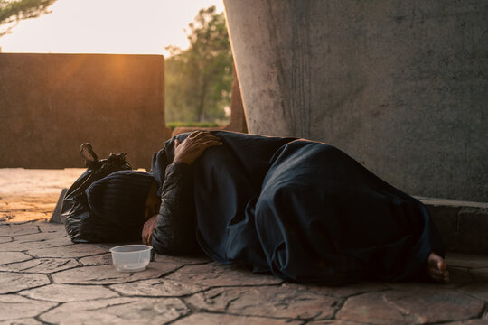 Homeless man on the street waiting for help food and money from people volunteer foundation donate. Poor tired stressed depressed hungry homeless man