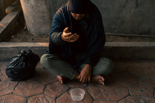 Homeless man on the street waiting for help food and money from people volunteer foundation donate. Poor tired stressed depressed hungry homeless man