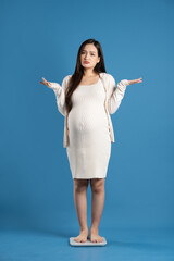 Portrait of pregnant asian woman, isolated on blue background