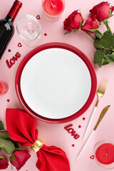 Special Valentine's Day feast. Top view vertical shot of plates, cutlery, hearts, red roses, present, wineglass, napkin, wine bottle, candles on pastel pink background