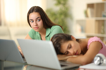 Perplexed student looking at her classmate sleeping