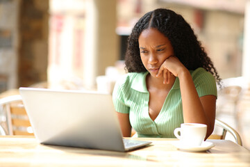 Serious black woman checking laptop in a bar - 706275994