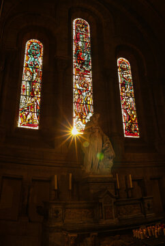 Virgin Mary and Jesus statue in Sacre Coeur church from Paris against star shaped sun passing through the painted stained glass. Concept photo for catholic religion.