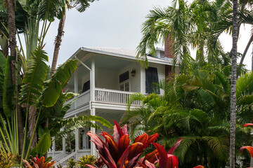 Typical wooden built, colonial style building, with a wrap around veranda, surrounded by tropical foliage