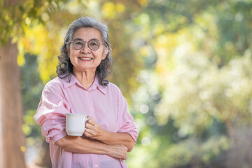 Comfort relaxed senior Asia woman drinking hot beverage tea coffee at garden. concept elderly people lifestyle.