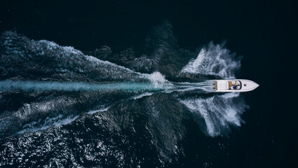 Large open white boat fast moving on dark water top view. White super high-speed boat in motion on...