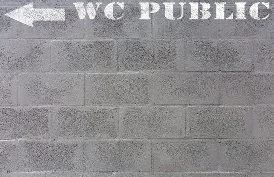Direction WC public, marquage sur mur de parpaings 