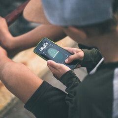 Teenager scan fingerprint to unlock the smartphone. Internet technology safety and privacy concept