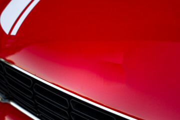 Compact, stylish and youthful five-door crossover in bright red color with white stripes across the entire body.