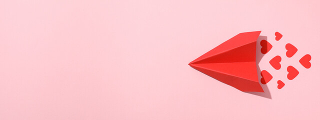 Red paper airplane with hearts on a pink background. - obrazy, fototapety, plakaty