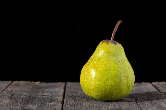 Yellow pear on wooden table on black background