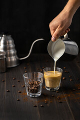 The process of hand pouring milk from a metal mug into a glass cup.Blending