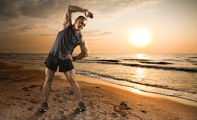 Athletic 50 year old male stretching on the beach