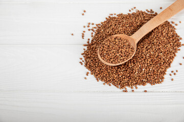 Raw buckwheat in a bowl on a textured wooden background. Wheat grains, porridge, cereals, raw buckwheat in a plate. Healthy food. Porridge. Diet. Organic cerea. Space for text.Copy space.