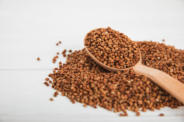 Raw buckwheat in a bowl on a textured wooden background. Wheat grains, porridge, cereals, raw buckwheat in a plate. Healthy food. Porridge. Diet. Organic cerea. Space for text.Copy space.