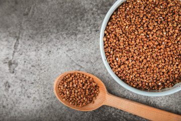 Raw buckwheat in a bowl on a textured wooden background. Wheat grains, porridge, cereals, raw buckwheat in a plate. Healthy food. Porridge. Diet. Organic cerea. Space for text.Copy space.