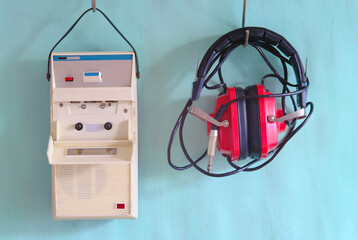 vintage cassette tape recorder and old red headphone on pastel green background.