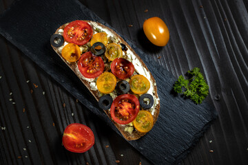 Top view open sandwich with cherry tomato on a black background.Bruschetta flat lay