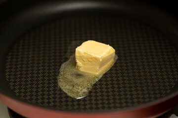 A piece of butter is melted in a non-stick frying pan